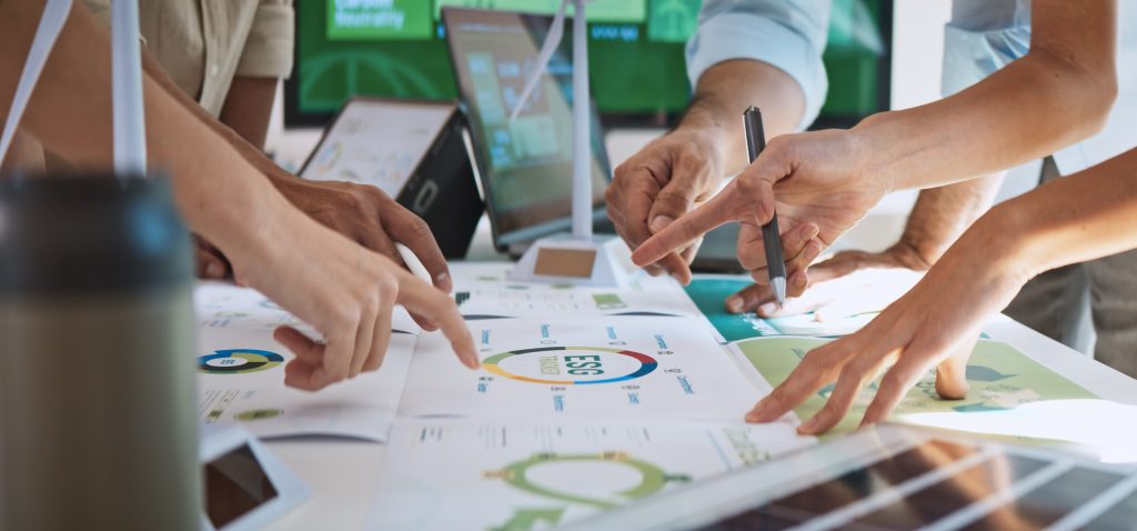 Manos de un equipo trabajando en un proyecto de sostenibilidad empresarial